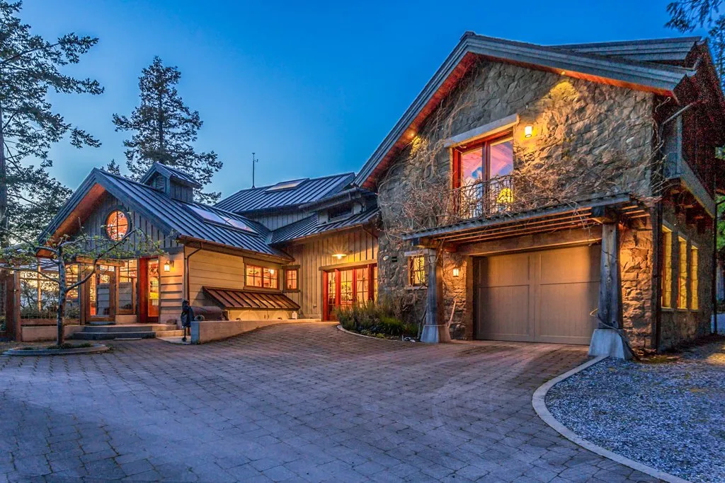 Full stone veneer gable and garage facade on a timber-framed home at dusk